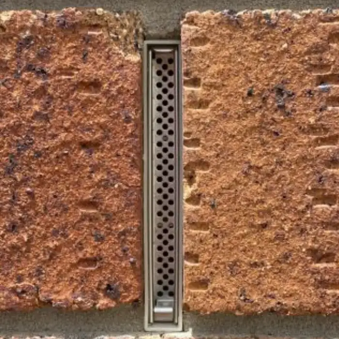 A weep vent installed in a wall with a protective grill.