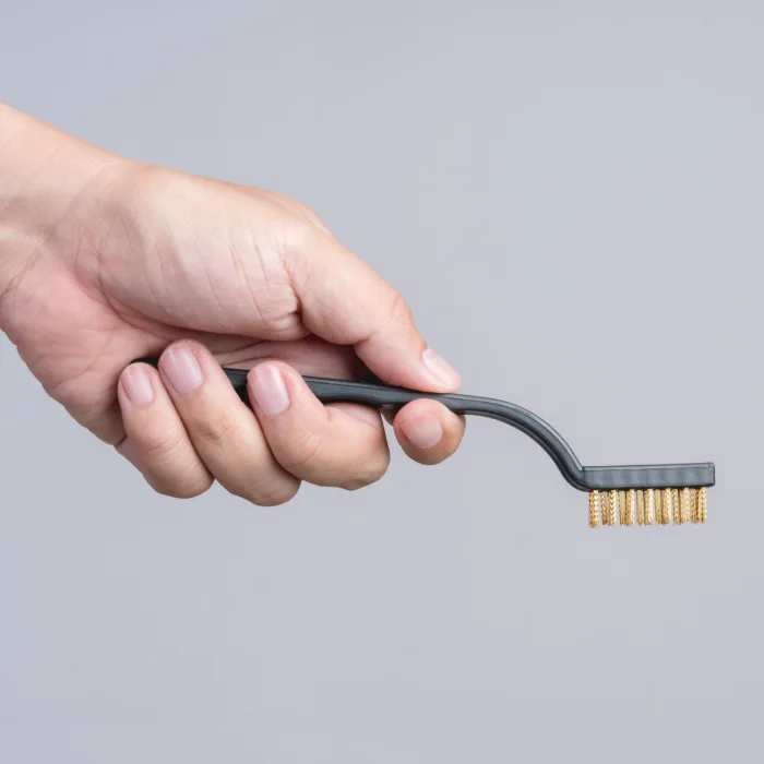 A wire brush held by a hand.
